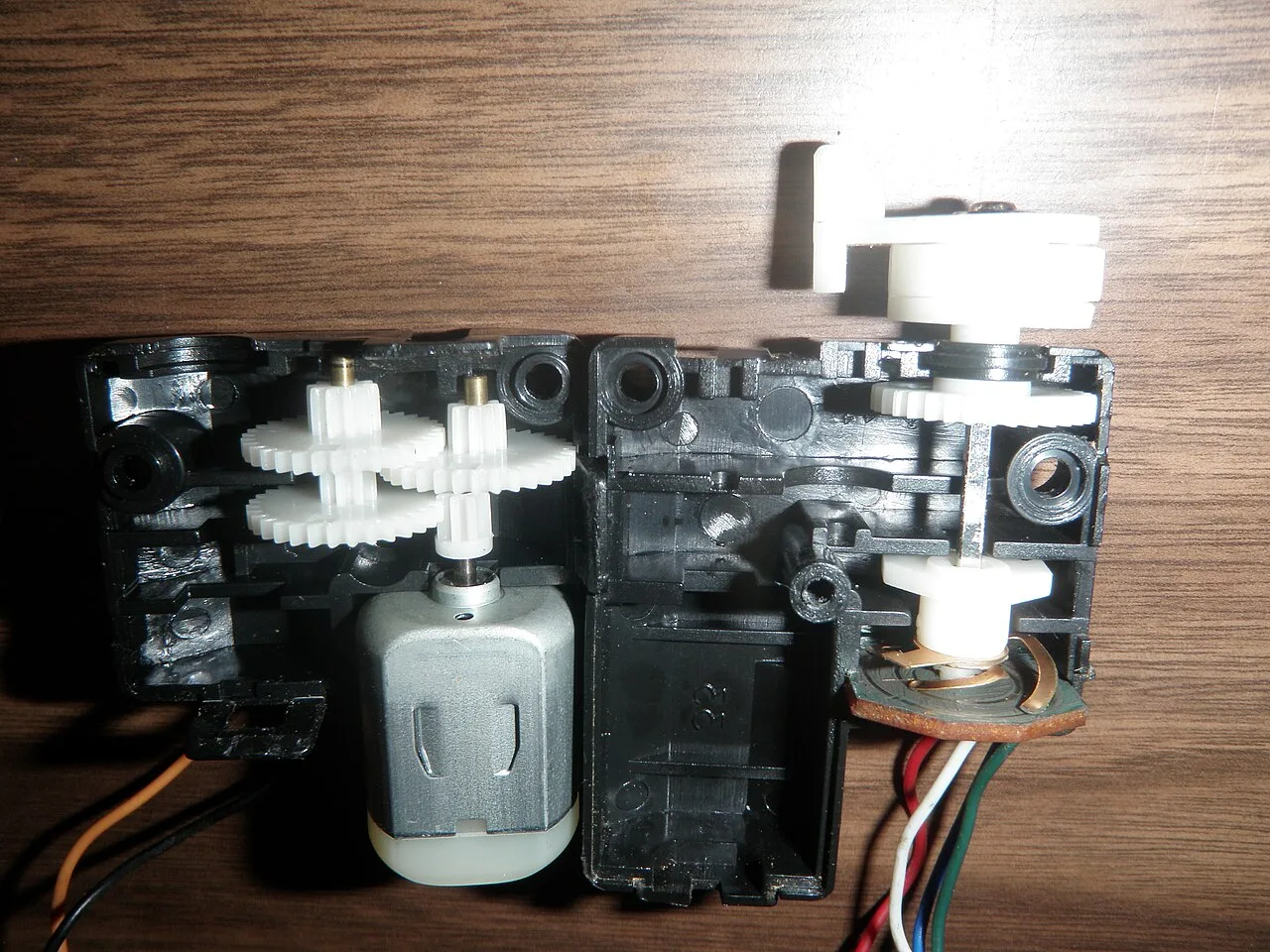 A radio-controlled car steering servo opened to show gears, motor and position feedback.